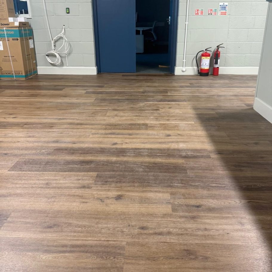 Commercial Deep Cleaning – Before Photo | Floor cleaning Interior view of a room with wooden flooring, blue walls, and a doorway.