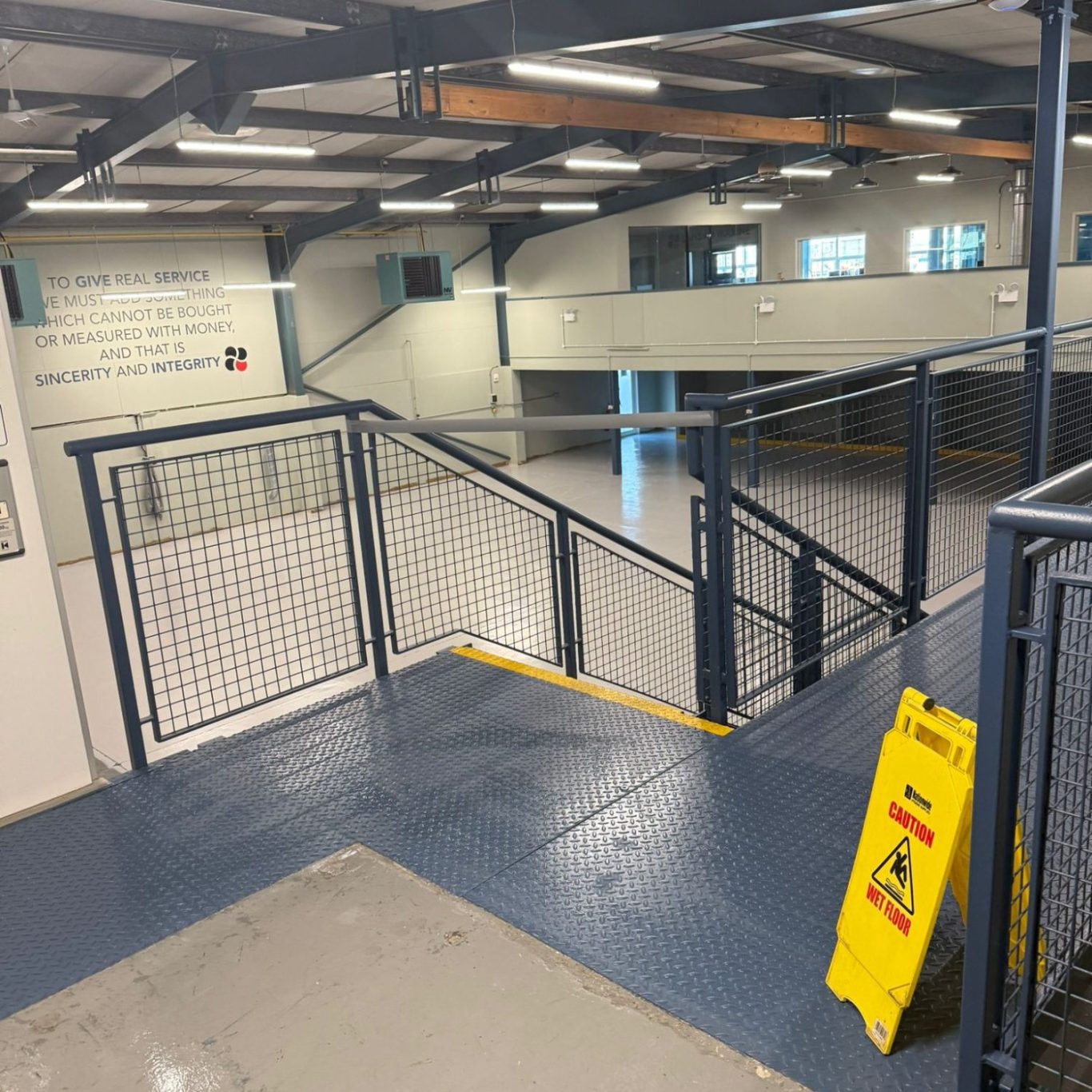 Commercial Cleaning | After Photo | Clean Indoor area with a railing and caution sign, featuring a smooth floor and angled ramps.