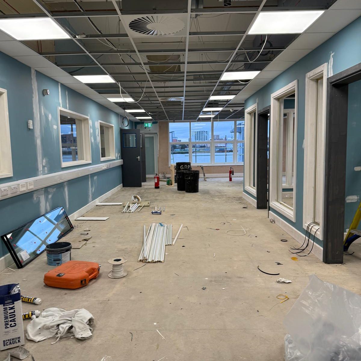 Commercial Deep Cleaning – Before Photo | Industrial site Under construction corridor with unfinished walls, flooring, and scattered tools.