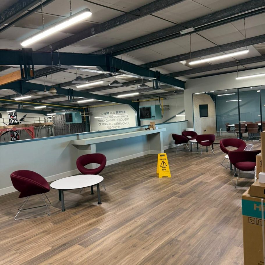 Commercial Deep Cleaning – After Photo | Professional Office Cleaning Results Spacious indoor area with seating, tables, and a caution sign on the floor.