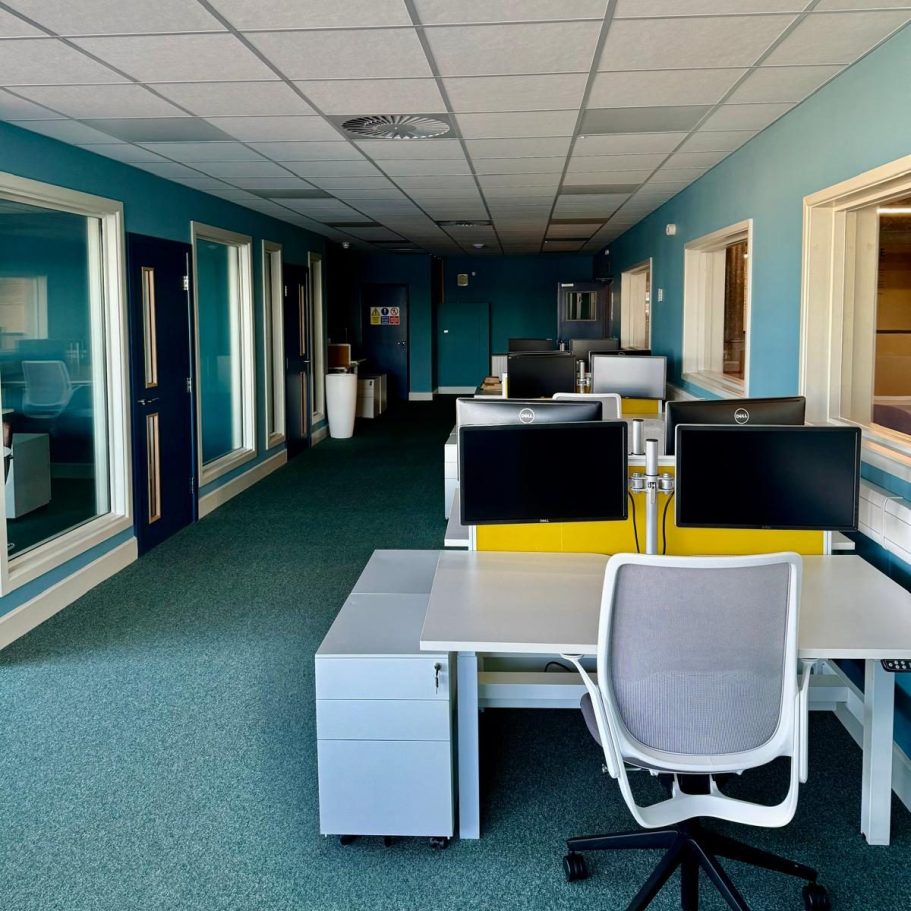 Commercial Deep Cleaning – After Photo | Industrial site Modern office space with desks, computers, and blue walls. Empty and well-lit.