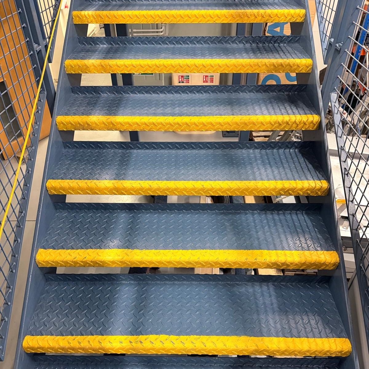 Commercial Deep Cleaning – After Photo | Professional Results/ Stairs Metal staircase with yellow-edged steps, leading upwards.
